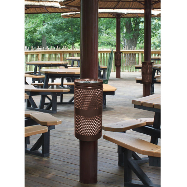 A Ex-Cell Kaiser round coffee waste receptacle with lid on a wooden deck with a picnic table.