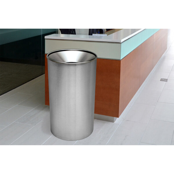 A Ex-Cell Kaiser stainless steel round waste receptacle in a lobby.