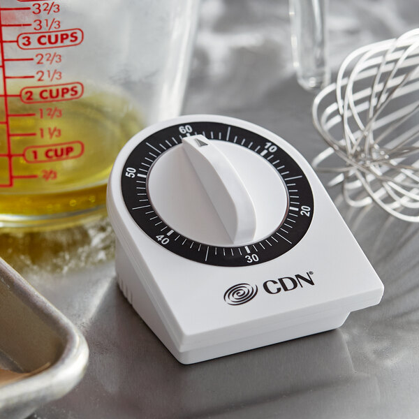 A white CDN MTM3 mechanical kitchen timer on a silver counter.