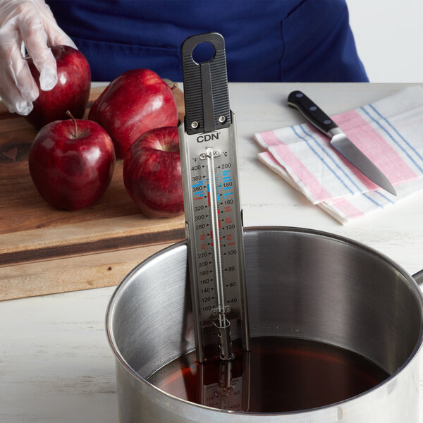 A CDN candy/deep fry paddle thermometer in a pot of liquid.