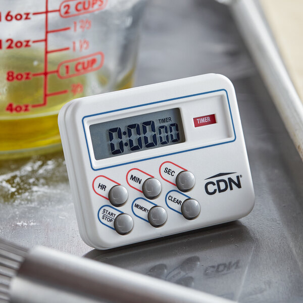 A white CDN digital kitchen timer sitting on a metal surface.