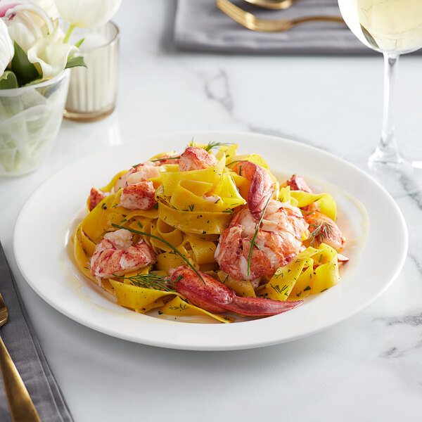 A plate of pasta with Boston Lobster Company lobster meat and herbs on a table.