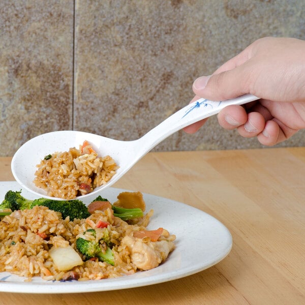 A hand using a Thunder Group Blue Bamboo rice ladle to serve rice onto a plate of food.