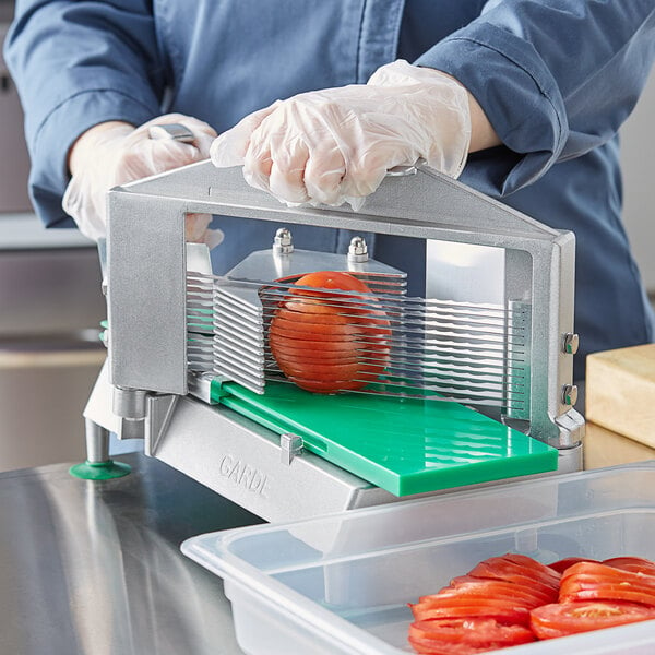 A person using a Garde XL tomato slicer to slice a tomato on a counter.