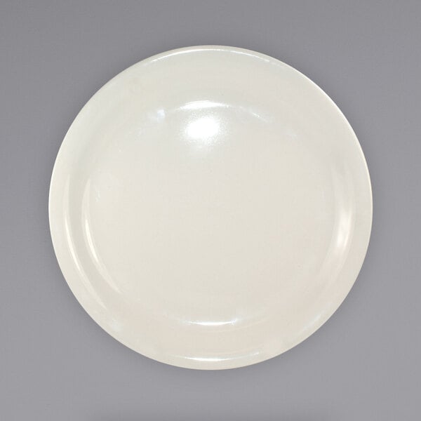 An International Tableware Valencia narrow rim stoneware plate in ivory on a white surface with a light reflection.
