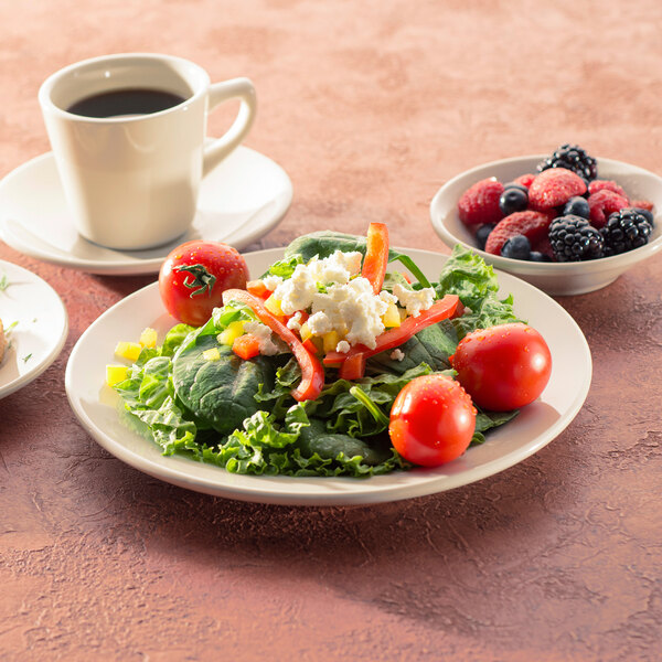 An International Tableware Roma stoneware plate with a salad and fruit on it.
