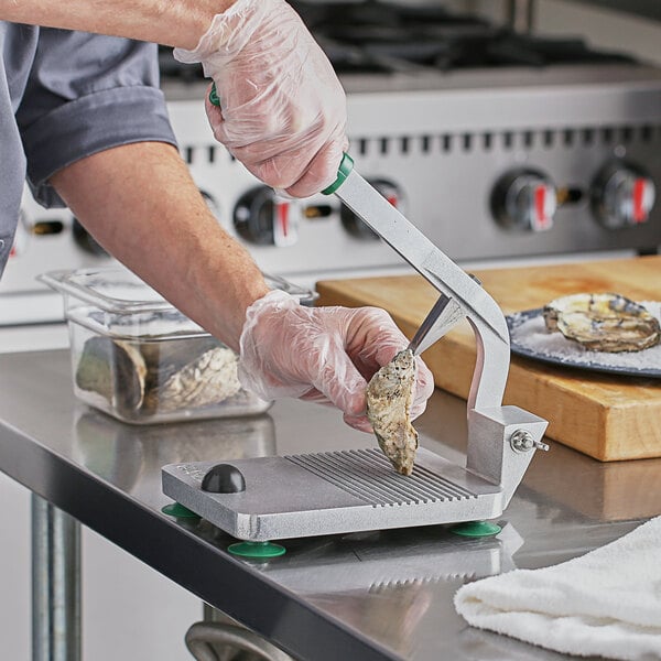 A person using a Garde oyster shucker to cut oysters.