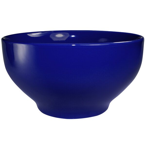 A cobalt blue stoneware footed bowl with white background.