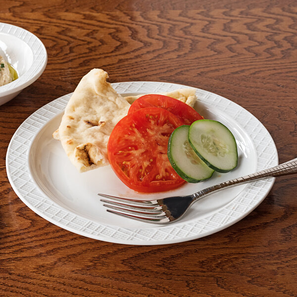 A Dresden porcelain plate with a slice of bread and cucumber on it with a fork.