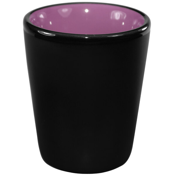 A black stoneware shot glass with a purple rim.