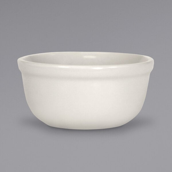 An ivory stoneware rimless soup bowl on a gray surface.