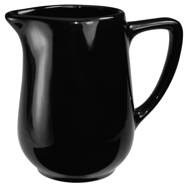 A black International Tableware Cancun stoneware creamer with a handle.