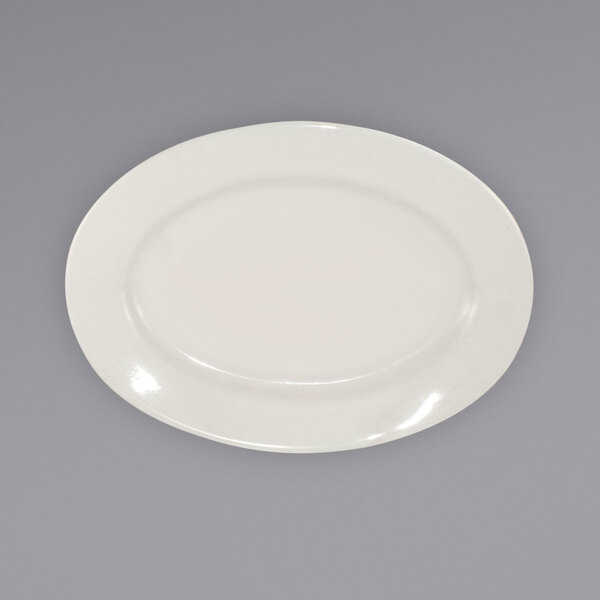 An International Tableware ivory stoneware platter with a wide rim on a gray surface.