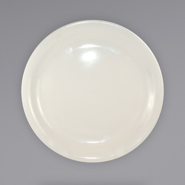 A close up of an International Tableware Valencia ivory stoneware plate with a rim.