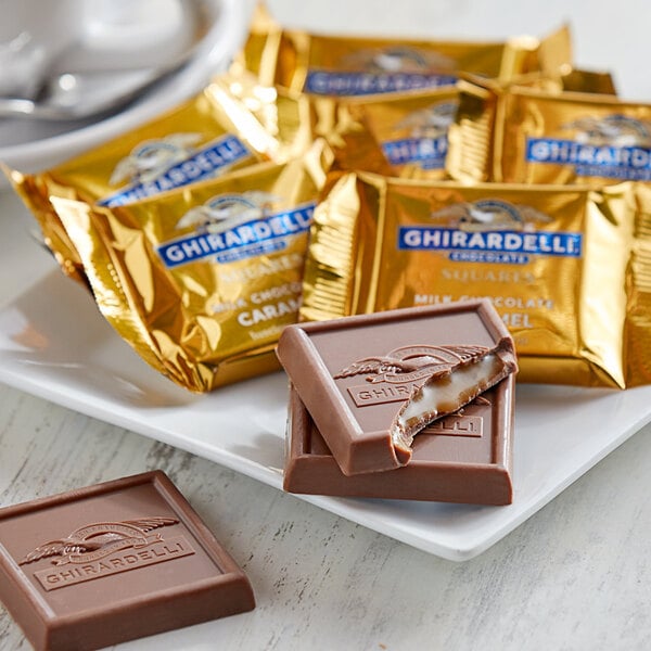 Ghirardelli Milk Chocolate Caramel Squares in gold foil packages on a plate.