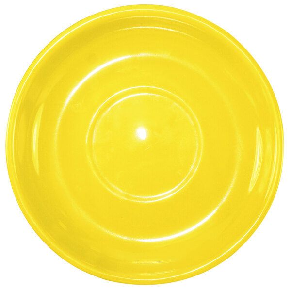 A yellow stoneware saucer with a light reflecting off the surface.