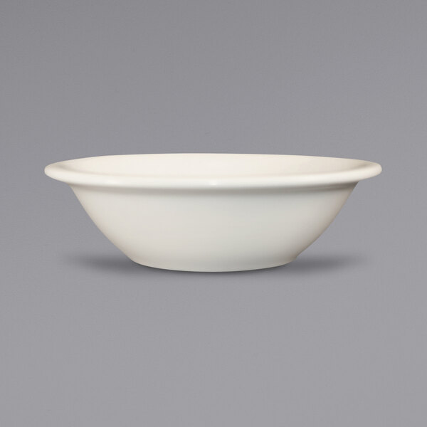 A Valencia ivory stoneware fruit bowl with a rolled edge on a gray surface.