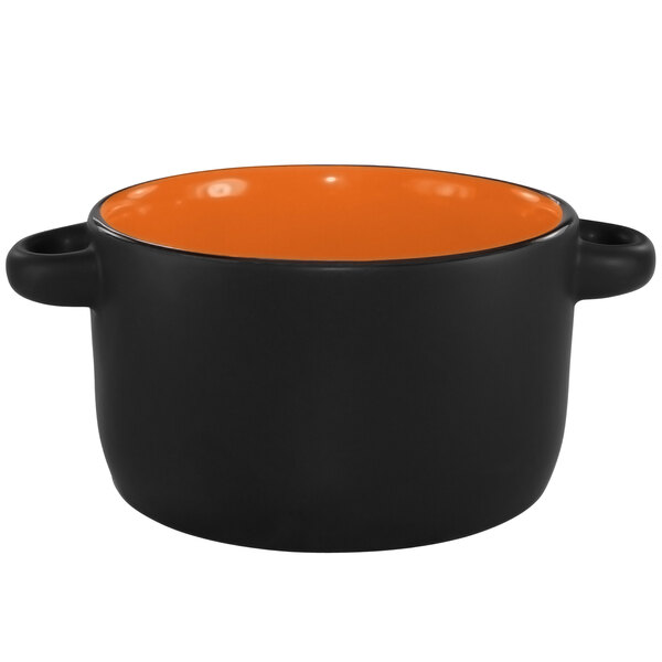An orange and black International Tableware Hilo stoneware bowl with a handle.