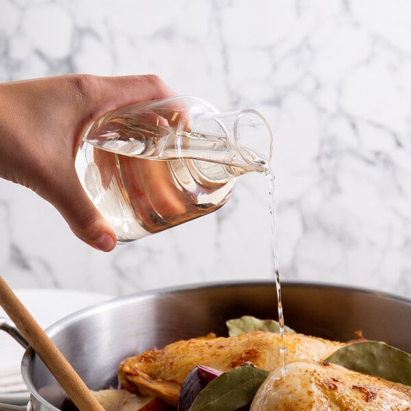 A hand pouring Admiration white cooking wine into a pot of food.