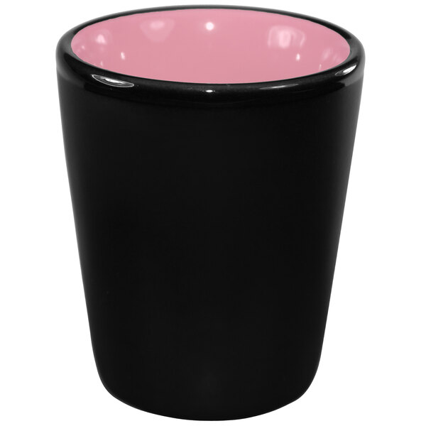 A black stoneware shot glass with a pink rim and interior.