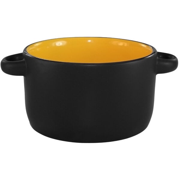 A black and yellow stoneware bowl with a handle.