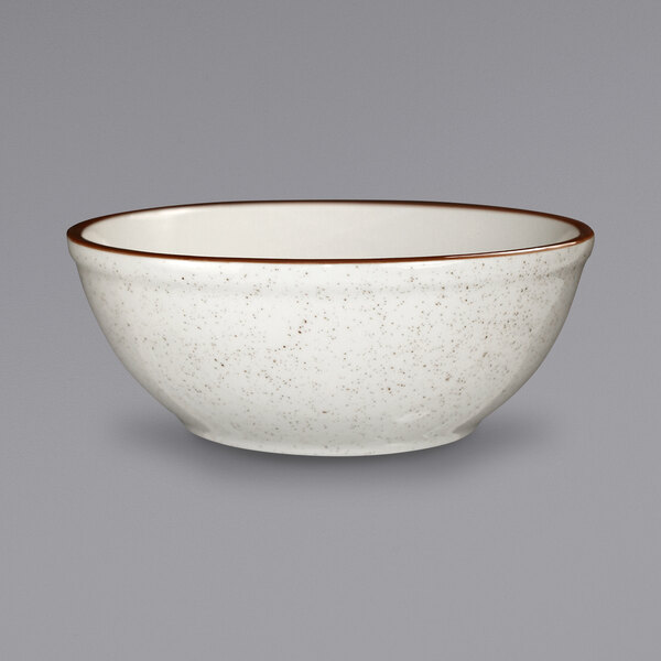 An ivory stoneware bowl with a brown speckled rim.