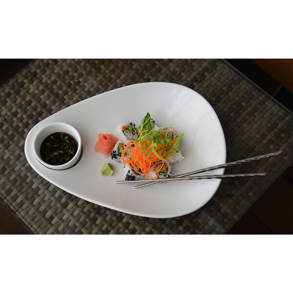 A white plate of sushi with a pair of stainless steel twisted chopsticks and sauce.