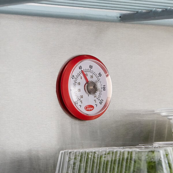 A Cooper-Atkins stick-on cooler thermometer on a plastic container.