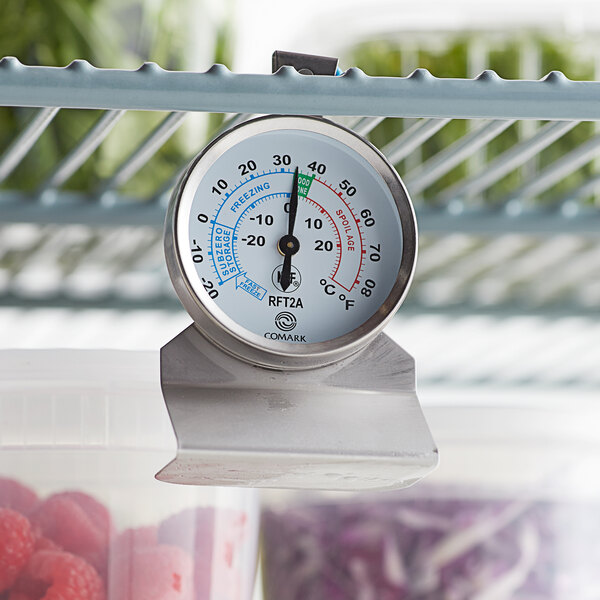 A Comark refrigerator/freezer thermometer on a shelf.