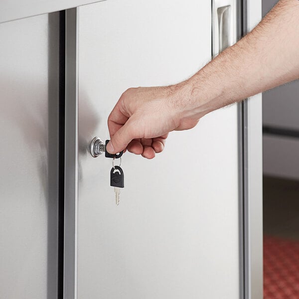 A hand using a Regency key to unlock a cabinet door.