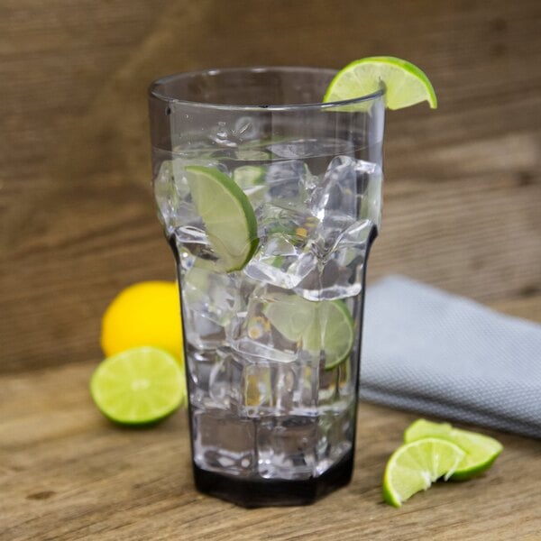 A Carlisle smoke plastic tumbler filled with water, ice, and lime slices.