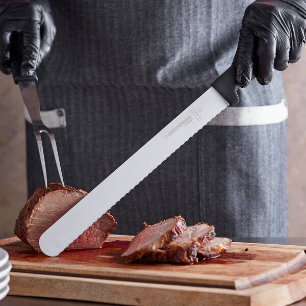 A person in black gloves using a Dexter-Russell SofGrip scalloped slicing knife to cut meat.