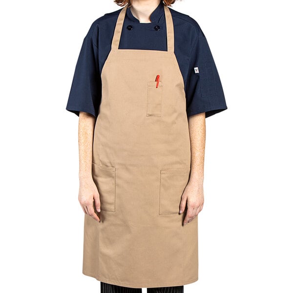 A woman wearing a khaki Uncommon Chef apron with three pockets.