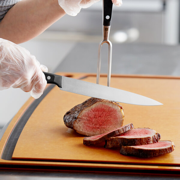 A person using a Wusthof carving knife to cut a piece of meat.