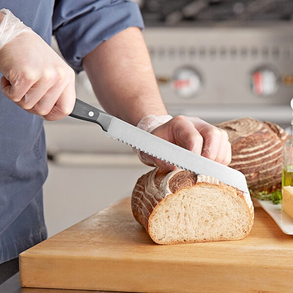A person using a Wusthof Gourmet serrated bread knife to slice bread.