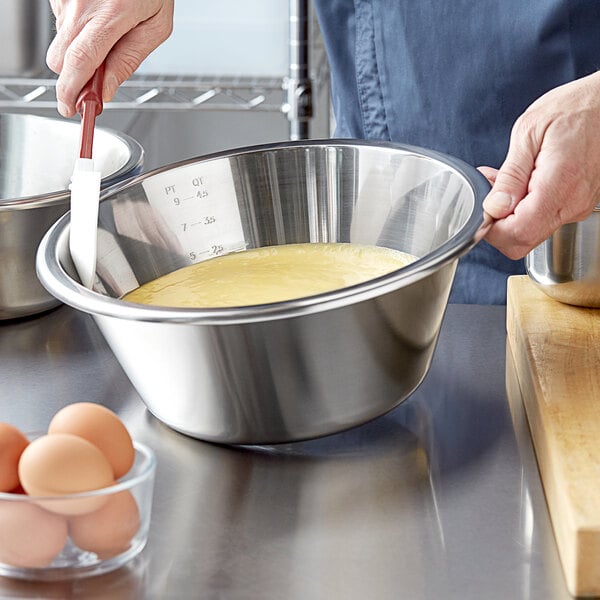 A person mixing eggs in a Linden Sweden stainless steel mixing bowl.