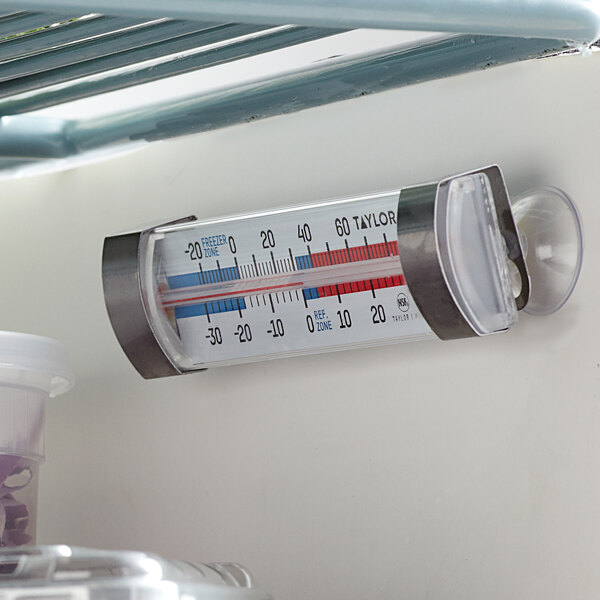 A Taylor refrigerator/freezer thermometer on a shelf in a refrigerator.