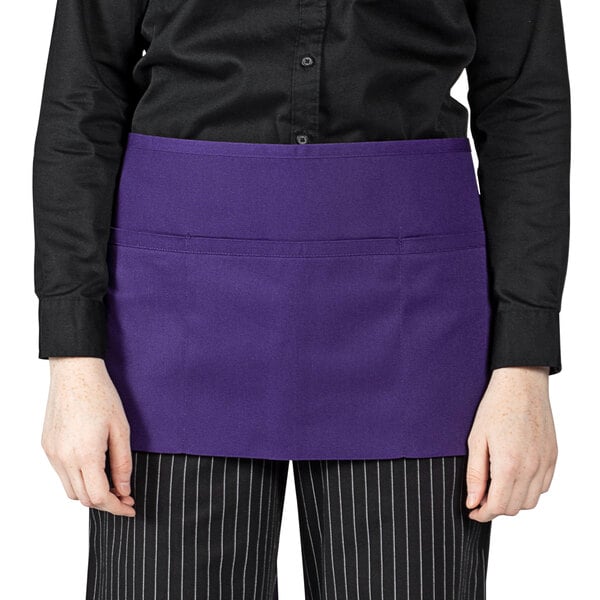 A woman wearing a Uncommon Chef purple waist apron with 3 pockets.