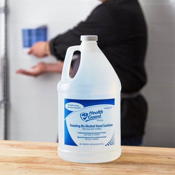 A man pouring Kutol Health Guard hand sanitizer from a gallon container on a counter.
