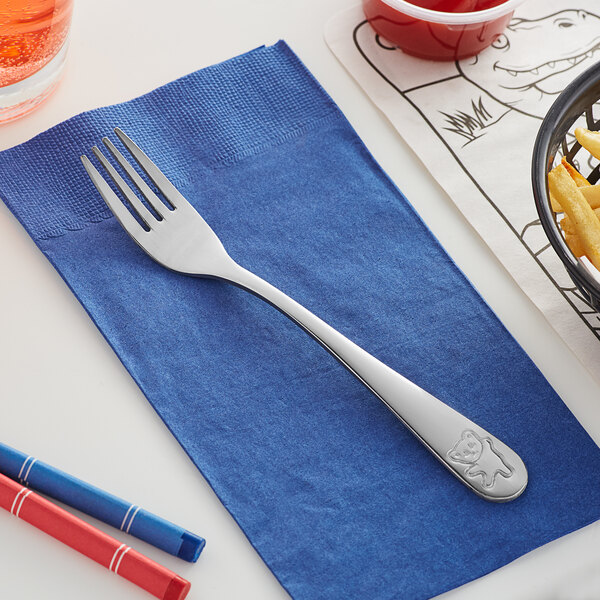 An Acopa stainless steel medium weight dinner fork on a napkin next to a bowl of french fries.