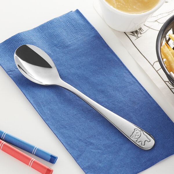 An Acopa medium weight stainless steel dinner spoon on a napkin.