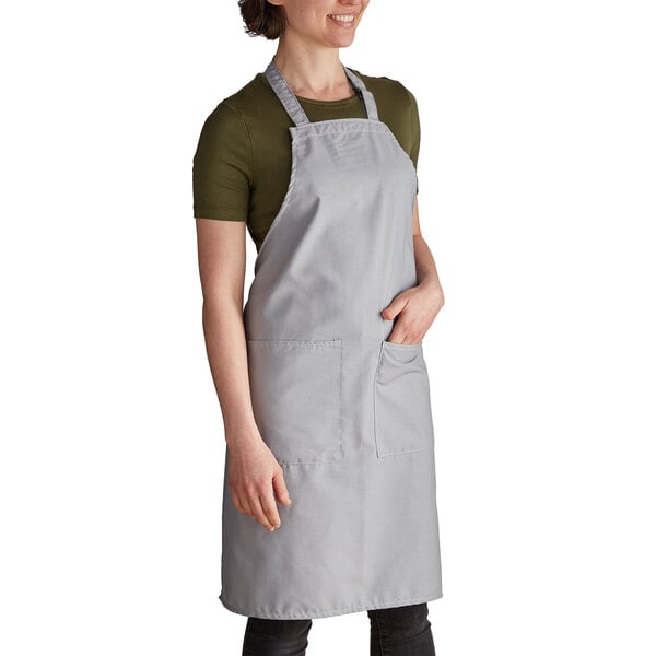 A woman wearing a gray Intedge bib apron with pockets.