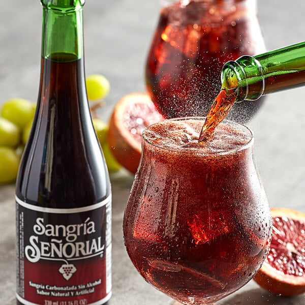 A green bottle of Sangria Senorial pouring into a glass of ice.