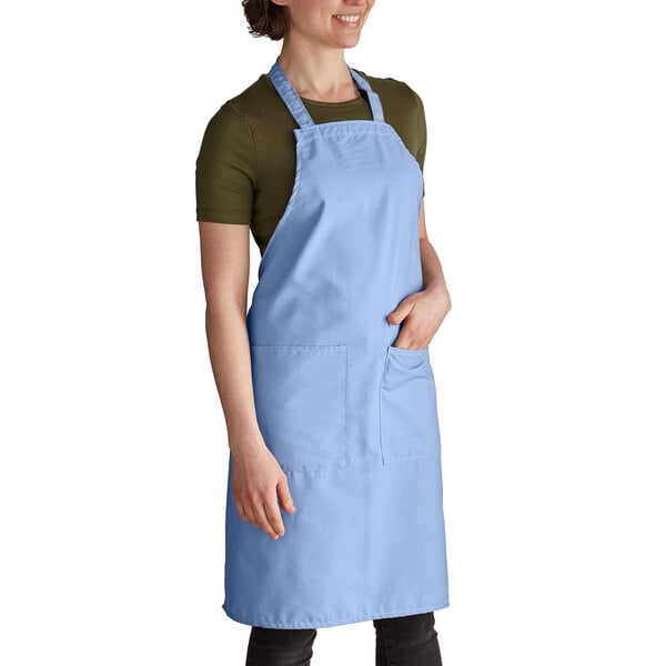 A woman wearing a light blue Intedge bib apron with pockets.