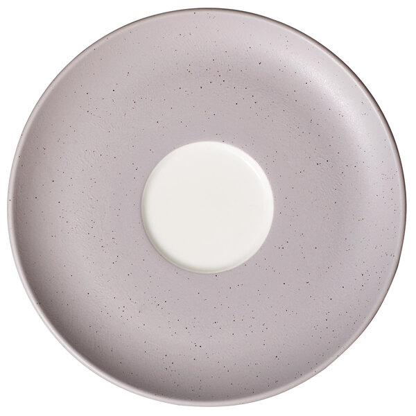 A white porcelain saucer with a gray speckle pattern and white rim with a small hole in the center.