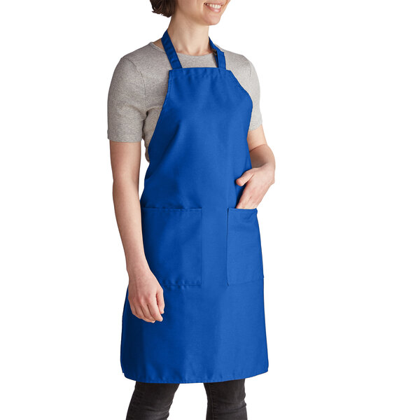 A woman wearing a royal blue Intedge bib apron with pockets.