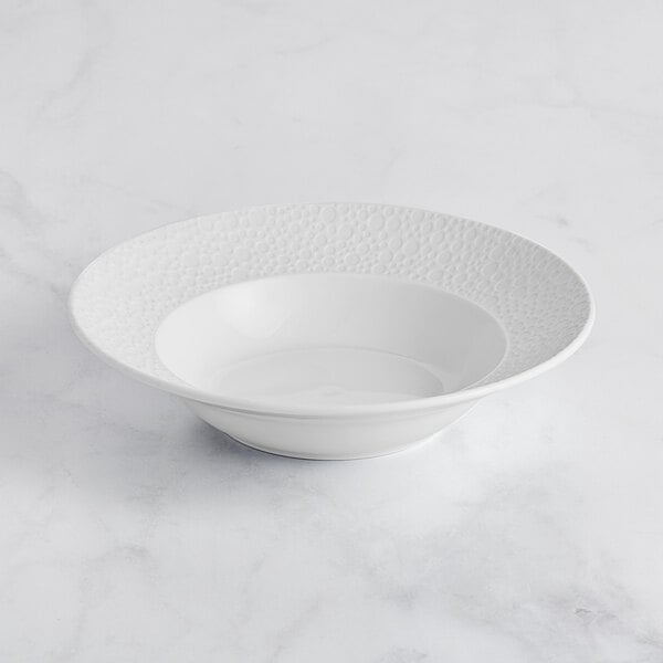 A Sant'Andrea Francia bright white porcelain pasta bowl with an embossed pattern.