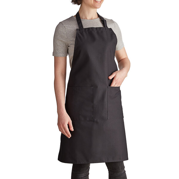 A woman wearing a black Intedge bib apron with pockets.