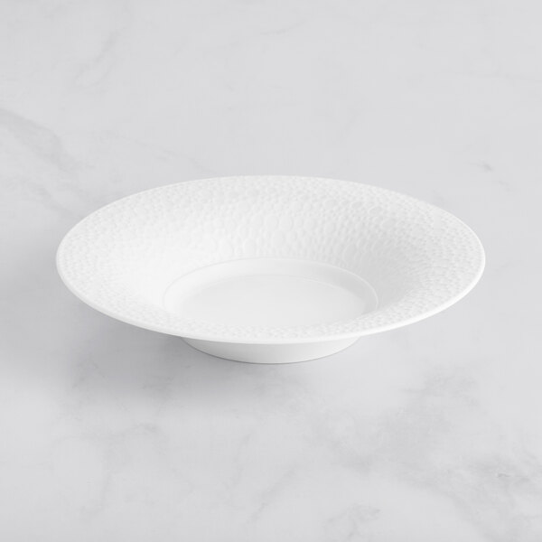 A Sant'Andrea Francia bright white porcelain bowl with an embossed pattern on a white surface.