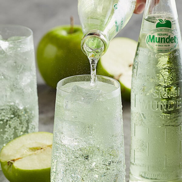 A person pouring Sidral Mundet Green Apple Soda into a glass